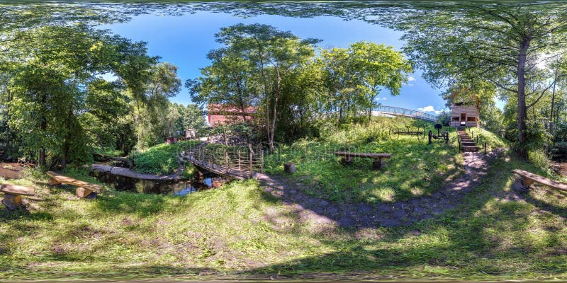 Full seamless spherical hdri panorama 360 degrees angle view among bushes and trees of resting place by old mill and narrow river