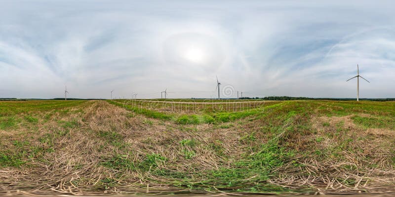 Full seamless spherical hdri panorama 360 degrees angle view near huge windmill propeller with halo in sky in equirectangular projection, VR AR virtual reality content. Wind power generation