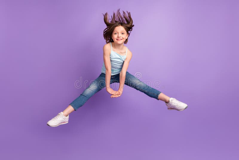 Full size photo of funky brown hairdo small girl jump hold hands wear blue top jeans isolated on violet color background