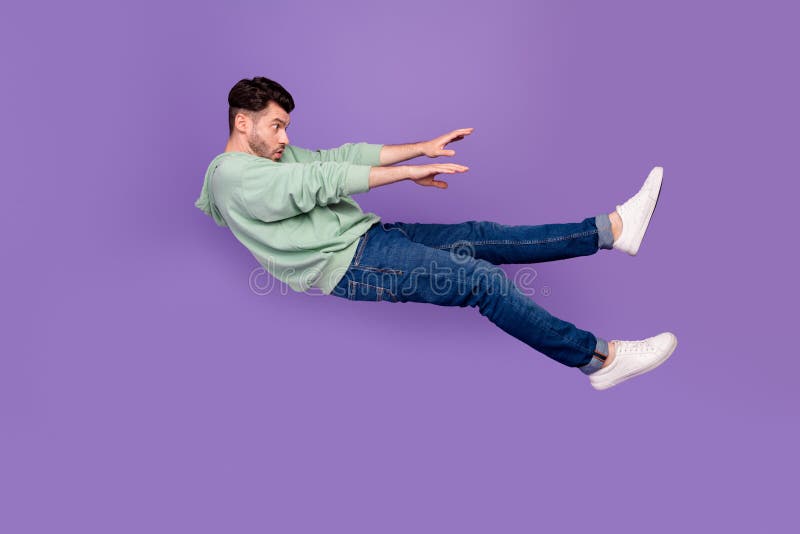 Full size photo of handsome young man flying away strong wind blow push dressed stylish khaki clothes isolated on purple