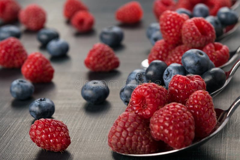 Full spoon with blue-berries and raspberries on a dark background stock photo Full spoon with blue-berries and raspberries on a dark background stock photo
