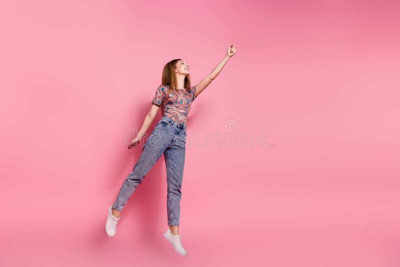 Full length photo of lovely teen lady jump fly superhero dressed stylish print clothes isolated on pink color background. Full length photo of lovely teen lady jump fly superhero dressed stylish print clothes isolated on pink color background.