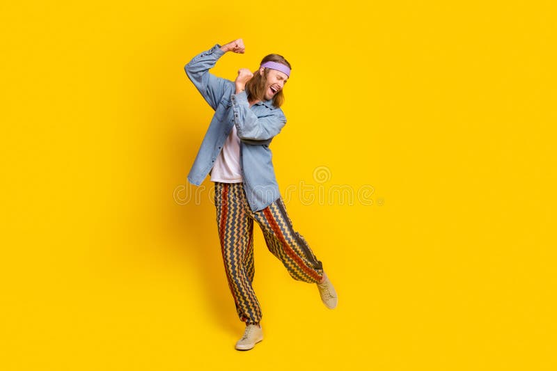 Full size photo of cool young man dancing empty space wear denim shirt isolated on yellow color background. Full size photo of cool young man dancing empty space wear denim shirt isolated on yellow color background.