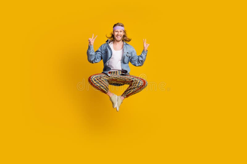 Full size photo of cool young man show v-sign jump empty space wear denim shirt isolated on yellow color background. Full size photo of cool young man show v-sign jump empty space wear denim shirt isolated on yellow color background.