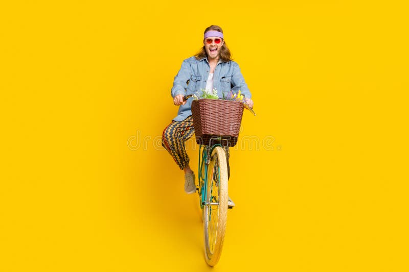 Full size photo of cool young man enjoy ride bicycle wear denim shirt isolated on yellow color background. Full size photo of cool young man enjoy ride bicycle wear denim shirt isolated on yellow color background.