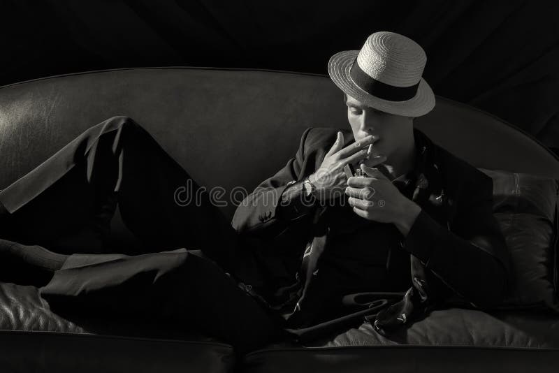 Fumeur élégant Jeune homme à la mode allumant une cigarette photographie stock libre de droits Fumeur élégant Jeune homme à la mode allumant une cigarette photographie stock libre de droits