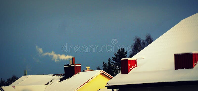 Fumo da una ciminiera, riscaldamento soffiatura del fumo Fumo che esce da una casa sul tetto contro un cielo blu d'inverno fotografia stock libera da diritti Fumo da una ciminiera, riscaldamento soffiatura del fumo Fumo che esce da una casa sul tetto contro un cielo blu d'inverno fotografia stock libera da diritti
