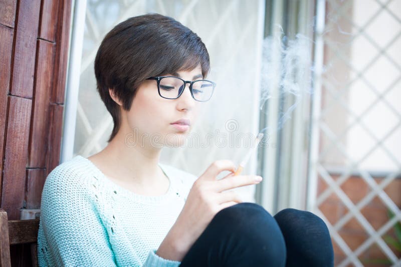Fumo exterior, cigarro da jovem mulher viciado imagem de stock Fumo exterior, cigarro da jovem mulher viciado imagem de stock