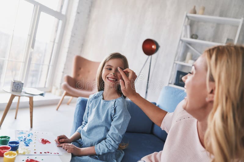 Fun time together. Mother giving her daughter faces paint and sm royalty free stock photography Fun time together. Mother giving her daughter faces paint and sm royalty free stock photography