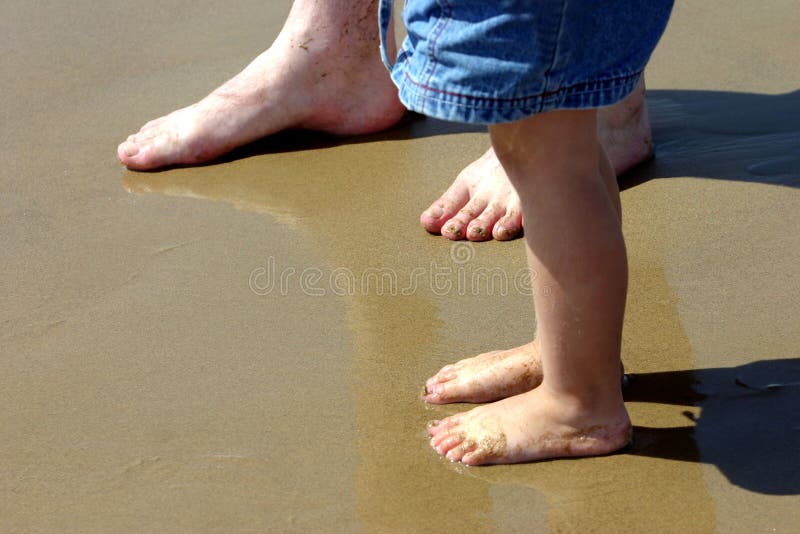 big and little feet in water on shore. big and little feet in water on shore