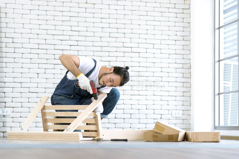 Funcionamento do homem novo como o trabalhador manual, tabela de madeira de montagem com equipm imagens de stock Funcionamento do homem novo como o trabalhador manual, tabela de madeira de montagem com equipm imagens de stock
