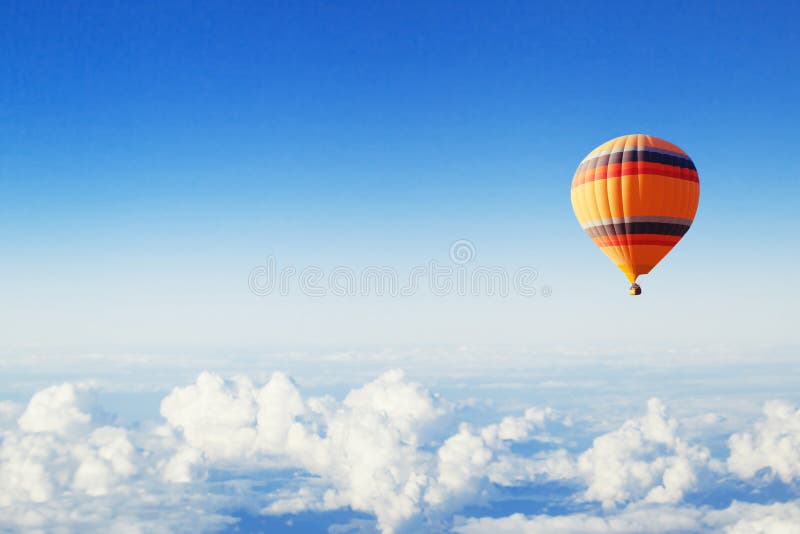 Inspiration or travel background, fly above the clouds, colorful hot air balloon in blue sky. Inspiration or travel background, fly above the clouds, colorful hot air balloon in blue sky