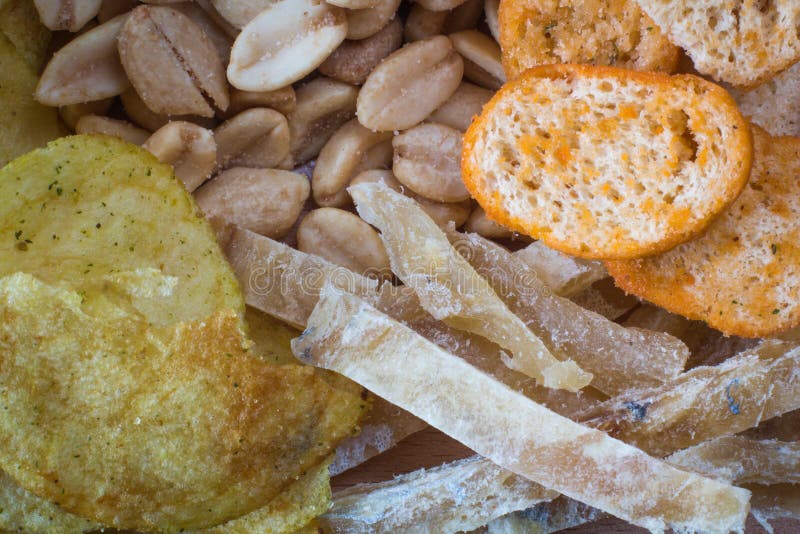 Fundo de microplaquetas de batata, de amendoins fritados, de fatias de peixes e de biscoitos Textura Close-up fotos de stock Fundo de microplaquetas de batata, de amendoins fritados, de fatias de peixes e de biscoitos Textura Close-up fotos de stock