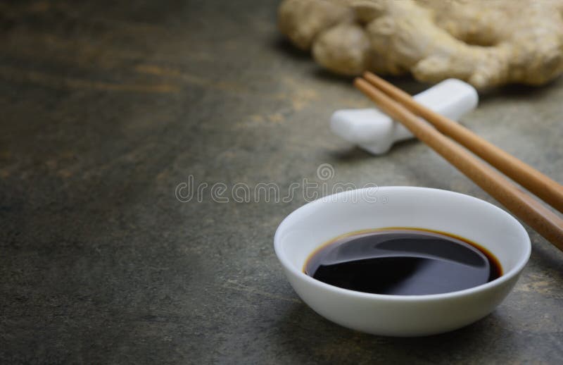 Soya sauce in a white bowl on a kitchen dark stone table top, front view background with a space for a text. Soya sauce in a white bowl on a kitchen dark stone table top, front view background with a space for a text