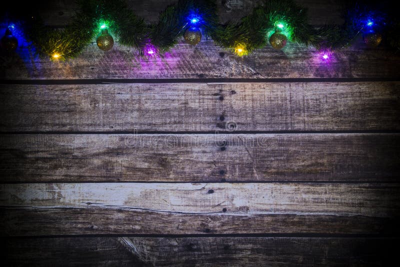 Fundo festivo do ano novo ou do Natal de placas de madeira velhas escuras, da festão de incandescência de luzes e de bolas colori imagens de stock Fundo festivo do ano novo ou do Natal de placas de madeira velhas escuras, da festão de incandescência de luzes e de bolas colori imagens de stock