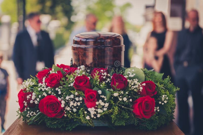 Funerary urn with ashes of dead and flowers at funeral