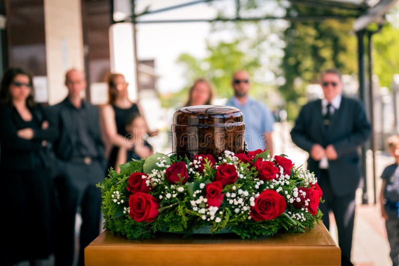 Funerary urn with ashes of dead and flowers at funeral