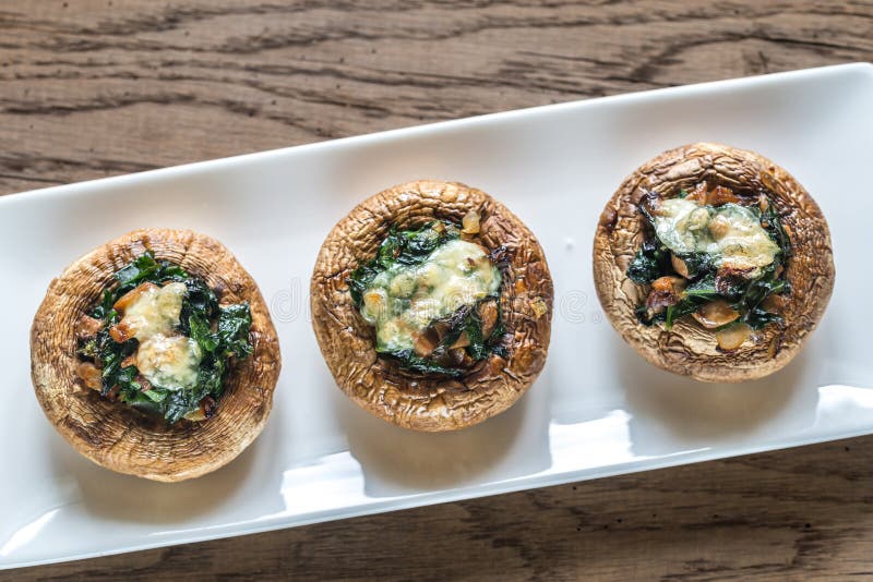 Funghi al forno farciti con spinaci e formaggio immagine stock Funghi al forno farciti con spinaci e formaggio immagine stock
