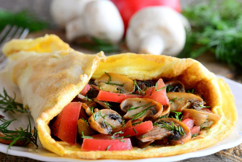 Funghi, omelette della prima colazione dell'omelette dei pomodori farcita con i funghi, pomodori ed aneto su un piatto e su un ve fotografia stock libera da diritti Funghi, omelette della prima colazione dell'omelette dei pomodori farcita con i funghi, pomodori ed aneto su un piatto e su un ve fotografia stock libera da diritti