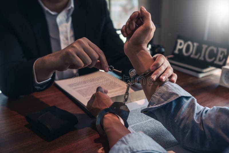 Police officer interrogating suspect or criminal man with handcuffs arrested at the investigation. Police officer interrogating suspect or criminal man with handcuffs arrested at the investigation.