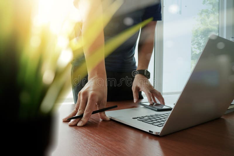 Funktionsduglig bärbar dator för märkes- hand med förgrund för grön växt på trä arkivbild Funktionsduglig bärbar dator för märkes- hand med förgrund för grön växt på trä arkivbild