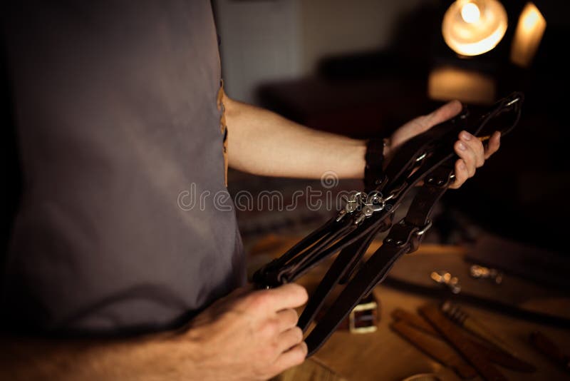 Funktionsduglig process av läderbältet i läderseminariet För fotograf` s för man hållande bälte för kamera Hjälpmedel på trä arkivbild Funktionsduglig process av läderbältet i läderseminariet För fotograf` s för man hållande bälte för kamera Hjälpmedel på trä arkivbild