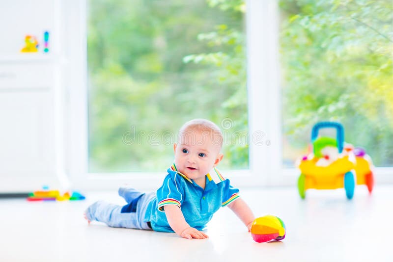 Funny baby boy playing with colorful ball and toy car