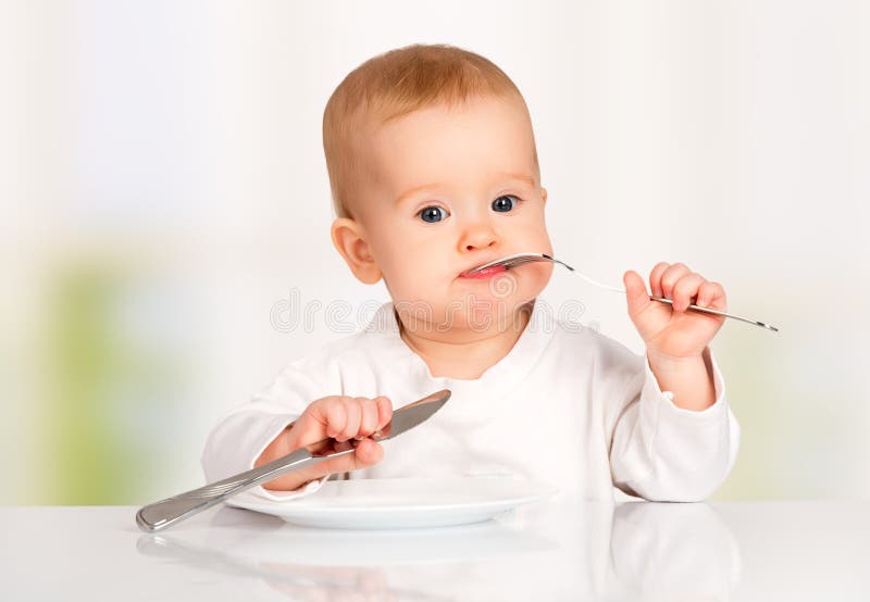 Funny baby with a knife and fork eating food