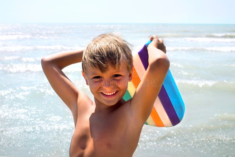Funny boy joking with kickboard on seashore. In a summer day stock photography Funny boy joking with kickboard on seashore. In a summer day stock photography