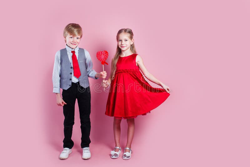 Funny boy and little girl with candy red lollipop in heart shape
