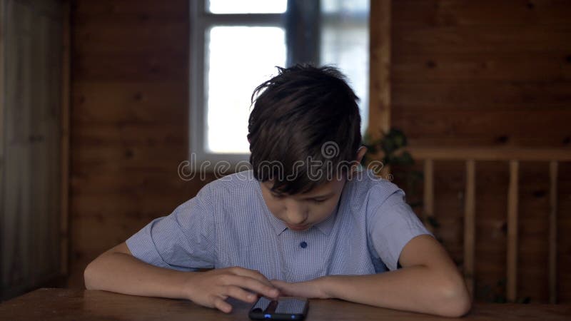 Мальчик сидит в телефоне. Мальчик сидит за столом фото. Мальчик 11 лет плачет. Фото подростка в толстовке сидит за столом.