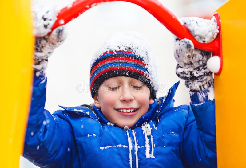 Funny Cheerful Boy in Jacket and Hat Playing Outdoors in Winter Stock