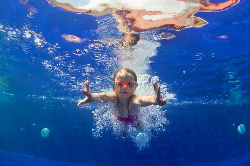 Funny child in goggles dive in swimming pool