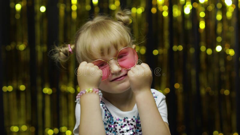 Funny child trying to fight at camera, boxing with expression. Girl posing on shiny background