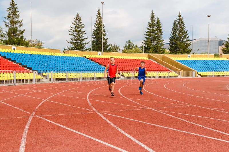 Funny children run a race around the sports stadium. children at the event. empty sports stands