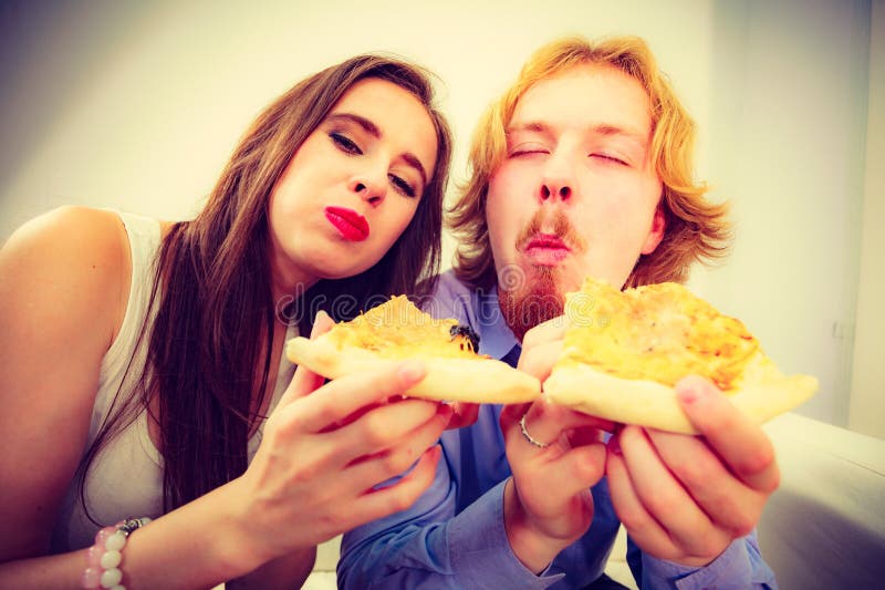 Funny couple eating pizza stock photography