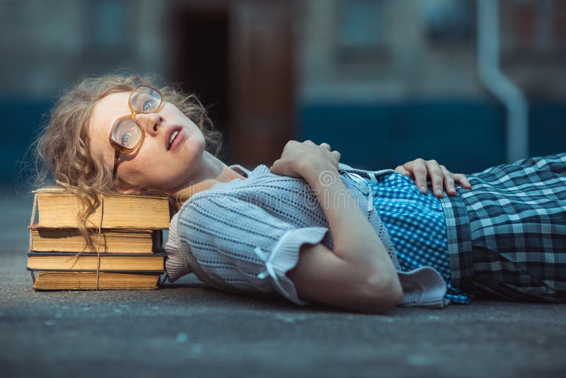 Funny crazy girl student with glasses lying on a pile of books stock photography