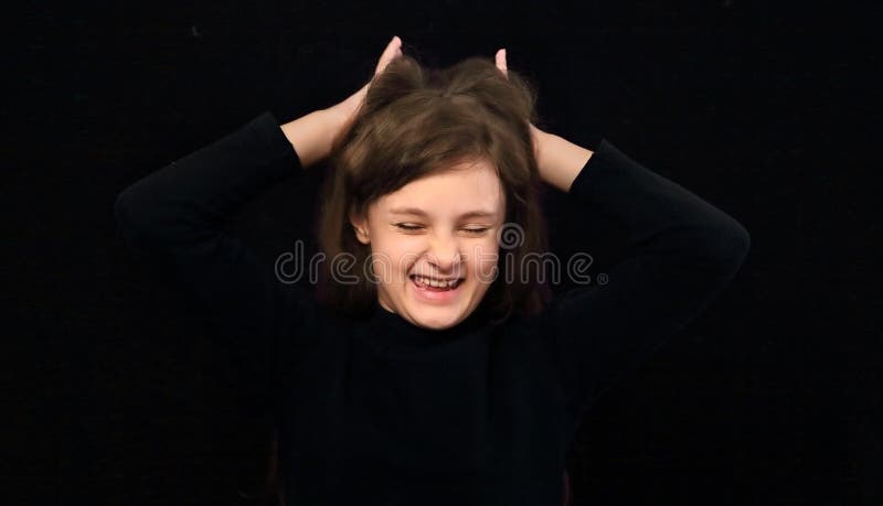 Funny crazy screaming kid girl with open mouth and holding the hands the head. Portrait on black background royalty free stock photo