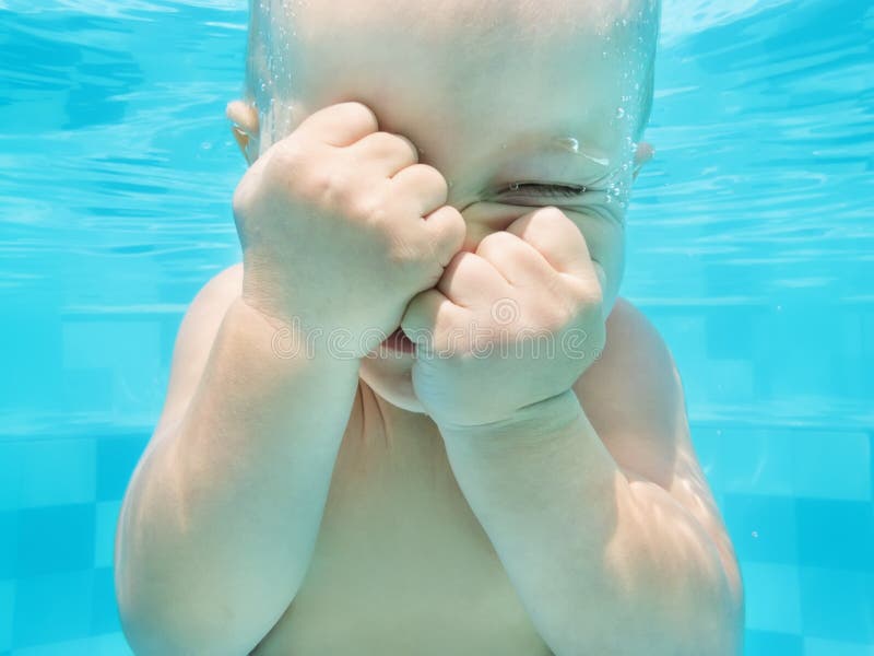 Funny face portrait of baby boy swimming and diving underwater stock photo