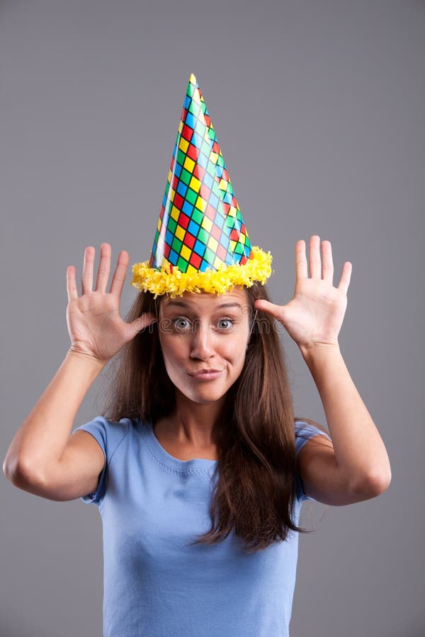 Funny faces and pointy hat. Party clown hat girl showing funny faces royalty free stock photography Funny faces and pointy hat. Party clown hat girl showing funny faces royalty free stock photography