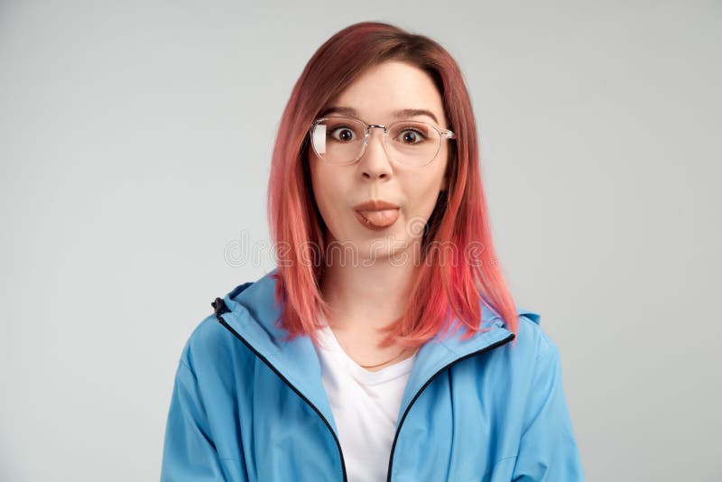 A funny girl in glasses makes faces and poses her face, sticking her tongue out. The concept of frivolous fun and teasing