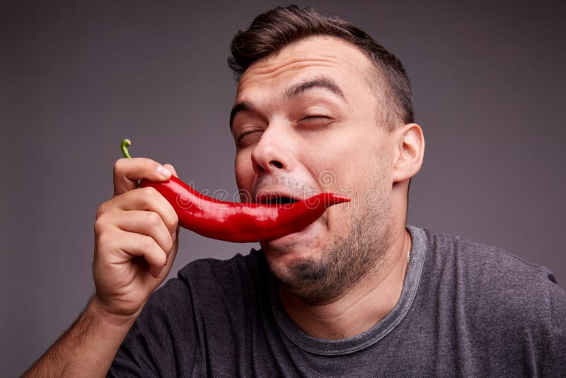 Funny Guy Eating Red Chili Pepper on a Gray Background. Handsome Man with  Spicy, Hot Pepper. Spiciness Concept. Stock Image - Image of head, food:  100230129