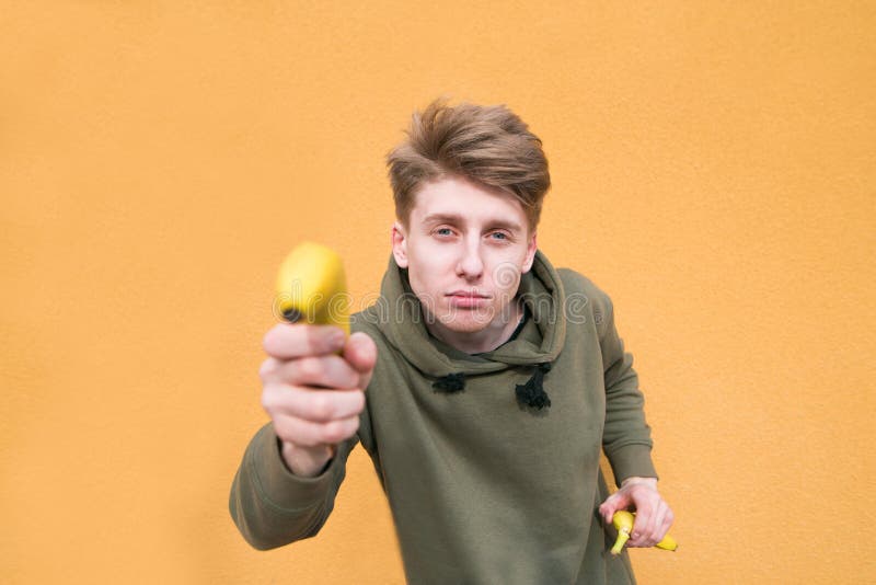Funny guy holds a banana in his arms and looks at the camera. 