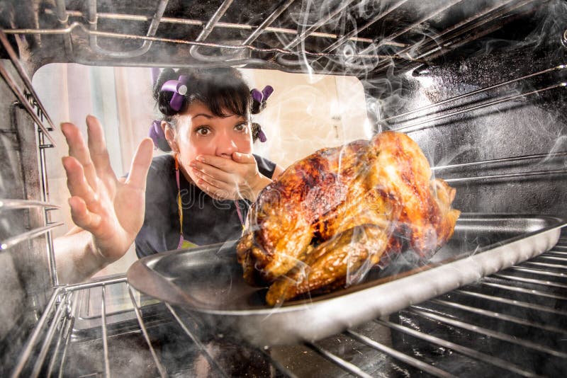 Lustige Hausfrau übersehen gebratenes Huhn in den Ofen, so hatte Sie versengt, Ansicht von der Innenseite des Ofens.