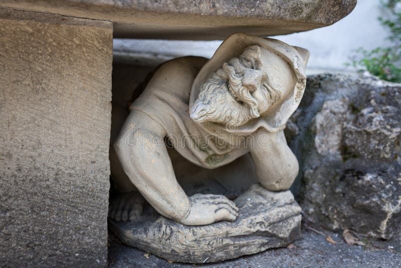 Funny human statue crouching under bench in garden royalty free stock images
