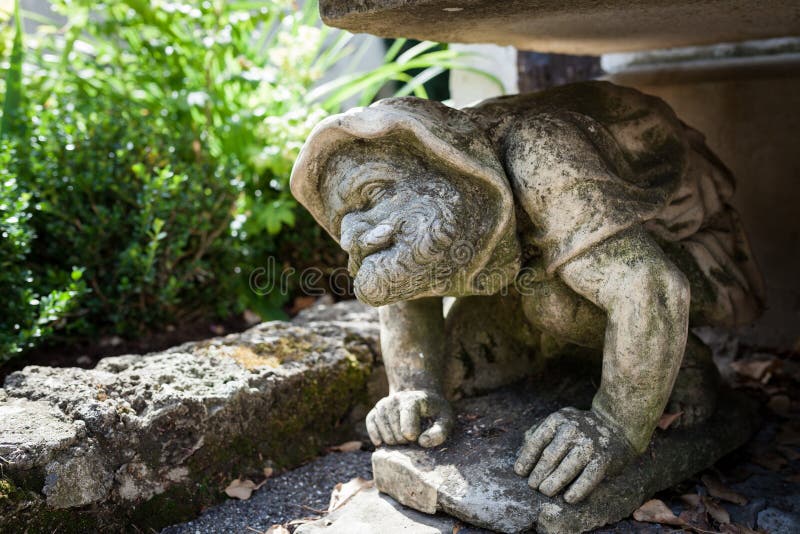 Funny human statue crouching under bench in garden royalty free stock photos
