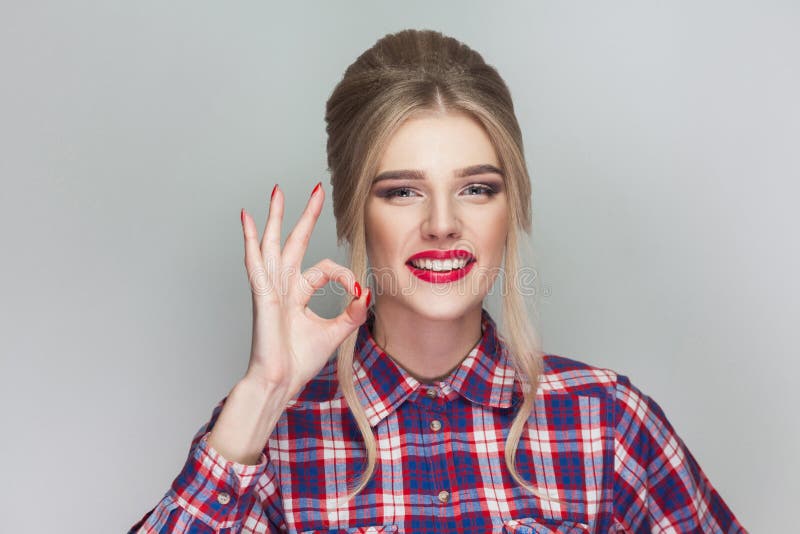 funny kissing beautiful girl with pink checkered shirt, collected updo hairstyle and makeup standing and showing Ok sign and look royalty free stock photos funny kissing beautiful girl with pink checkered shirt, collected updo hairstyle and makeup standing and showing Ok sign and look royalty free stock photos