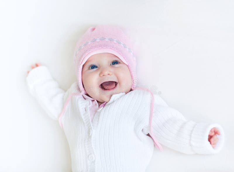 Funny laughing baby girl in white knitted sweater