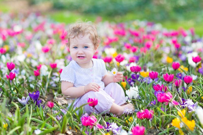 Funny laughing baby playing with first spring flowers royalty free stock images