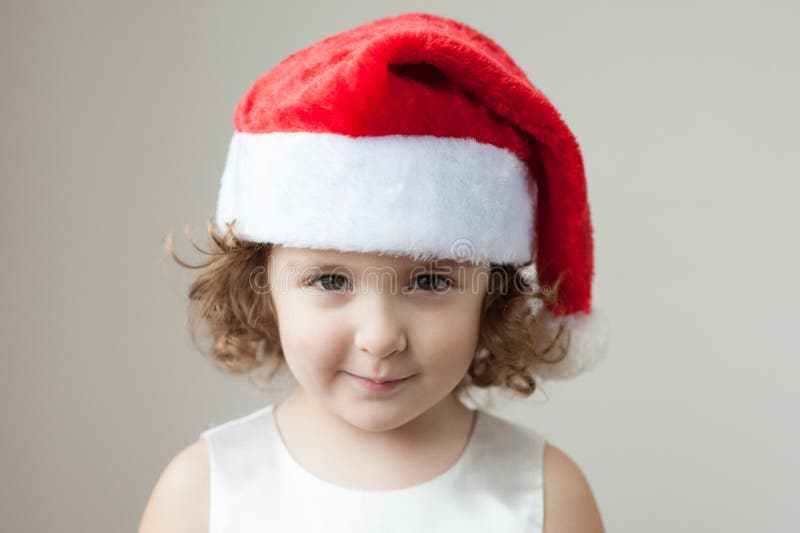 Funny little curly blonde girl in a Santa hat